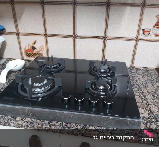 כיריים גז שחורות על משטח מטבח עם אריחים מעוצבים